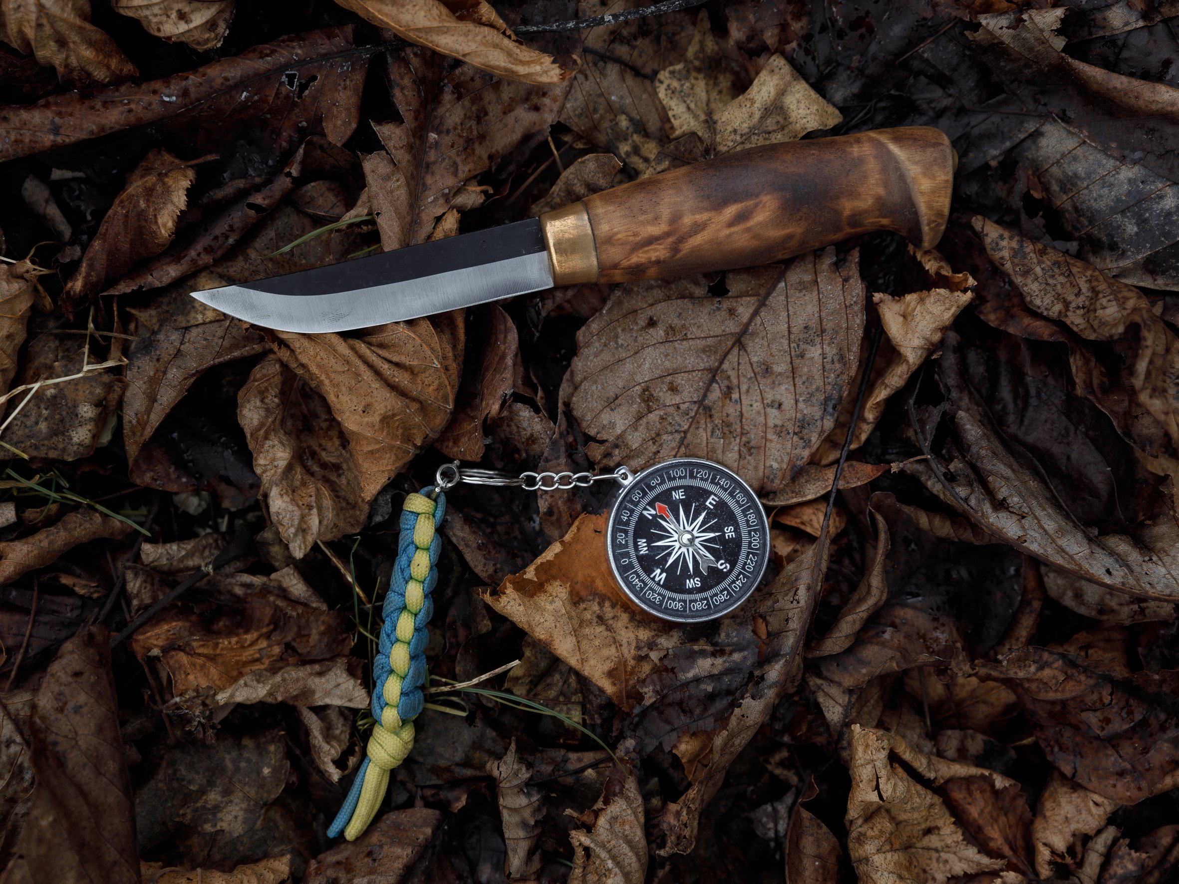 Compass and survival knife on fallen leaves. Tools for Hiking and survival